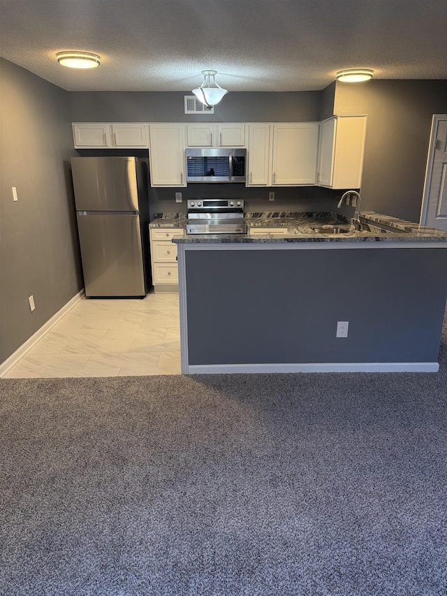 kitchen with kitchen peninsula, white cabinetry, sink, and appliances with stainless steel finishes