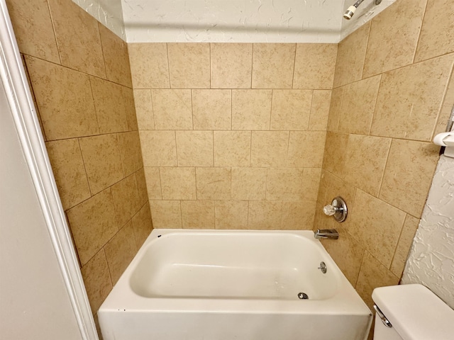 bathroom featuring tiled shower / bath combo and toilet