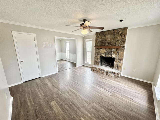 unfurnished living room featuring dark hardwood / wood-style floors, ceiling fan, ornamental molding, a textured ceiling, and a fireplace