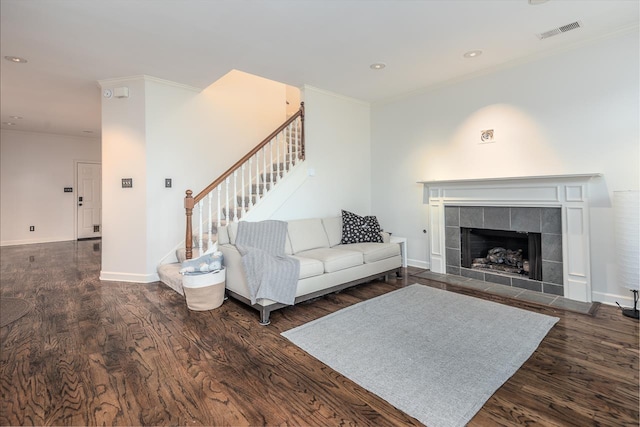 living room featuring a tile fireplace, dark hardwood / wood-style flooring, and crown molding