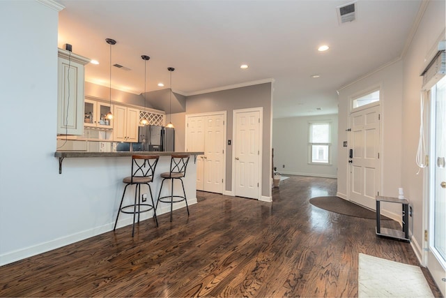 kitchen featuring cream cabinets, dark hardwood / wood-style floors, decorative light fixtures, kitchen peninsula, and stainless steel refrigerator