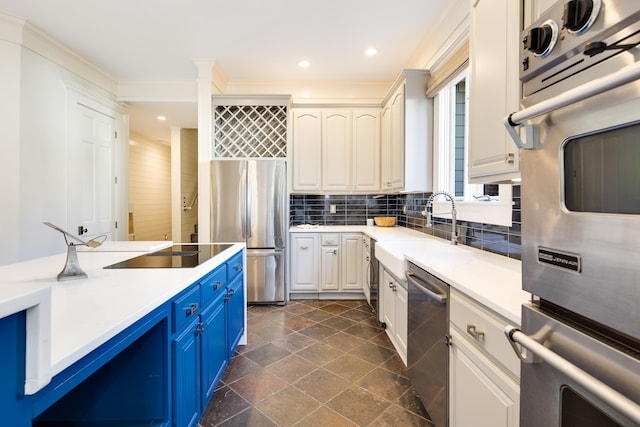 kitchen with blue cabinetry, sink, decorative backsplash, appliances with stainless steel finishes, and ornamental molding