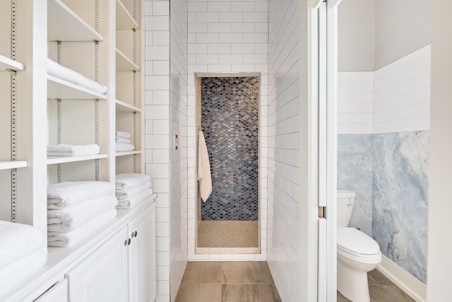 bathroom with tiled shower, vanity, and toilet