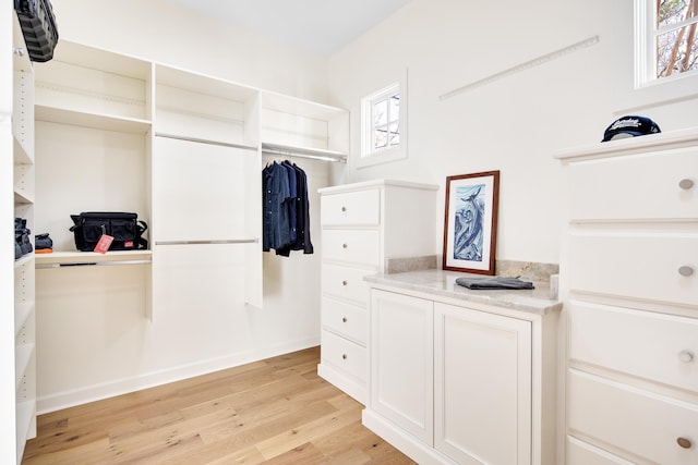 walk in closet with light hardwood / wood-style floors