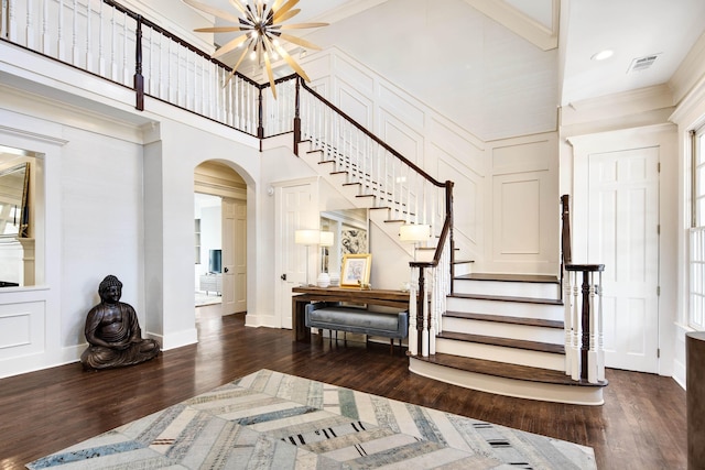 foyer entrance featuring dark hardwood / wood-style flooring, a high ceiling, and ornamental molding