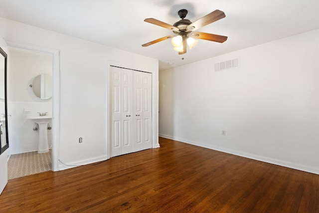 unfurnished bedroom featuring a closet, ensuite bath, ceiling fan, and hardwood / wood-style floors