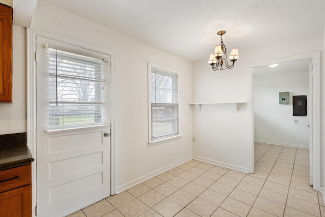 doorway to outside featuring a chandelier, light tile patterned floors, electric panel, and a wealth of natural light