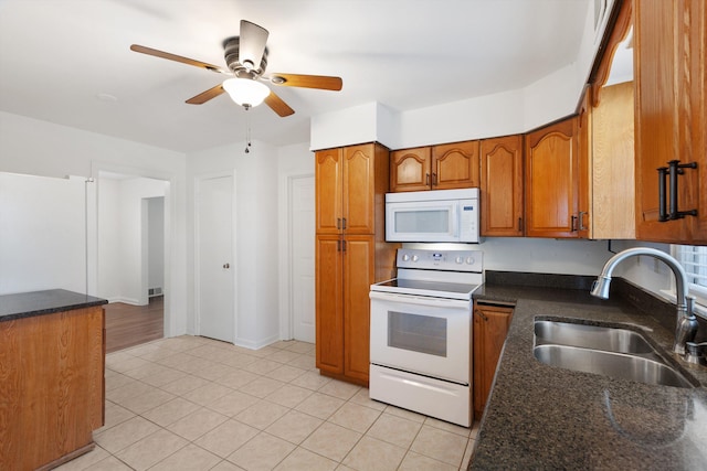 kitchen with dark stone counters, white appliances, ceiling fan, sink, and light tile patterned floors