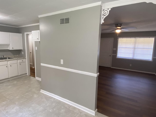 kitchen with ceiling fan, sink, white cabinetry, and ornamental molding