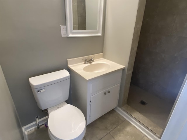 bathroom featuring a tile shower, tile patterned flooring, vanity, and toilet