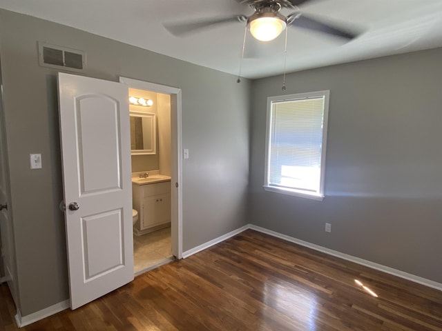 unfurnished bedroom with ceiling fan, dark hardwood / wood-style flooring, sink, and ensuite bath