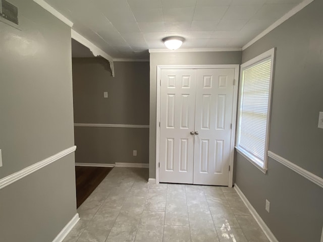 corridor with ornamental molding and light tile patterned floors