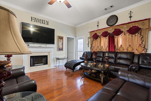 living room with wood-type flooring, a textured ceiling, ceiling fan, and ornamental molding