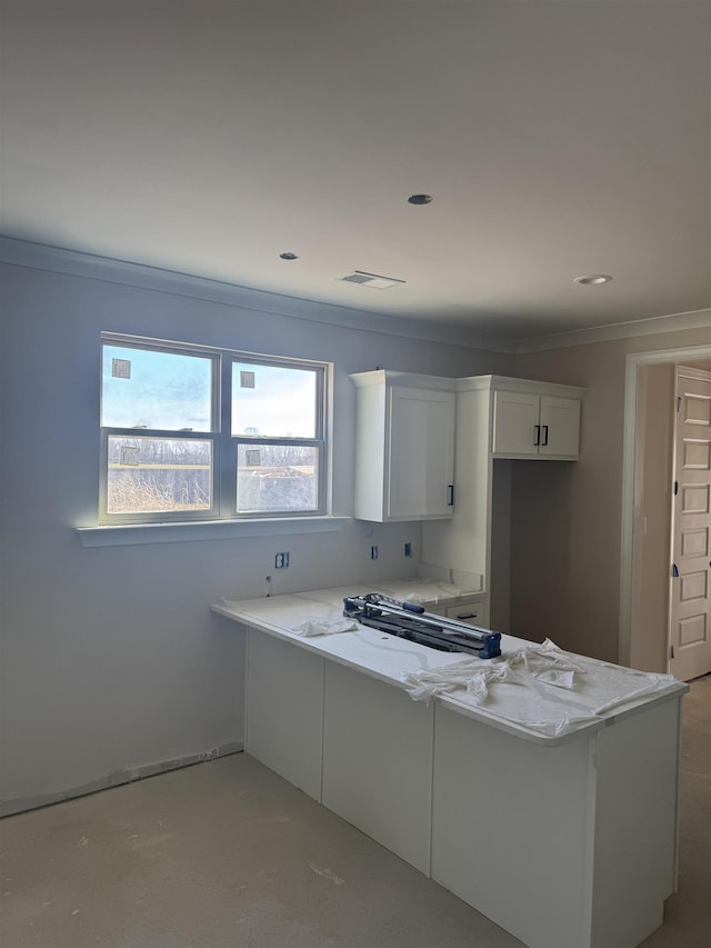 kitchen featuring crown molding, kitchen peninsula, light stone countertops, and white cabinets