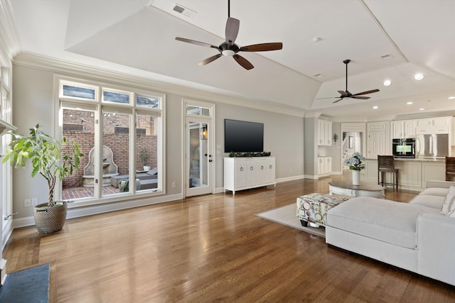 living room featuring hardwood / wood-style floors, ceiling fan, ornamental molding, and a tray ceiling