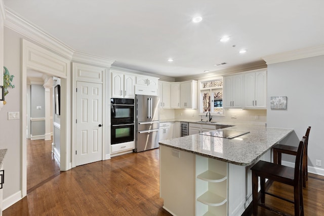 kitchen featuring kitchen peninsula, sink, black appliances, white cabinets, and a breakfast bar area