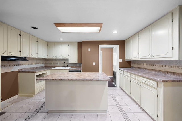 kitchen featuring sink, a center island, backsplash, and light tile patterned flooring