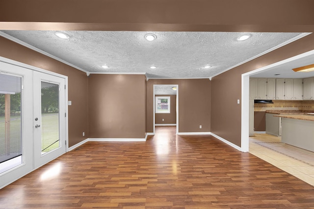 unfurnished living room featuring french doors, light hardwood / wood-style floors, a textured ceiling, and ornamental molding