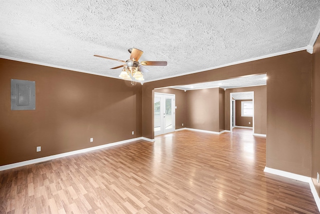 empty room with electric panel, ceiling fan, crown molding, and light hardwood / wood-style flooring