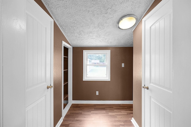 bedroom with light wood-type flooring, a textured ceiling, and vaulted ceiling