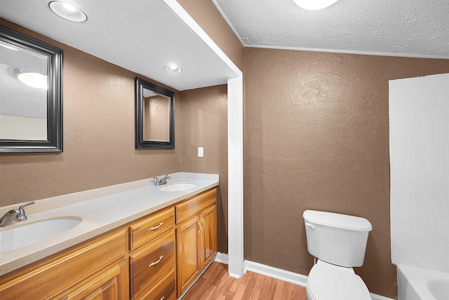 bathroom with crown molding, a textured ceiling, toilet, vanity, and hardwood / wood-style flooring