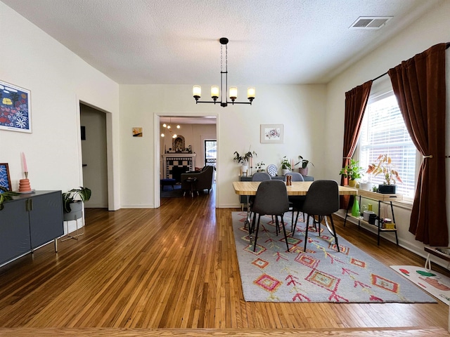 dining space with a textured ceiling, plenty of natural light, dark wood-type flooring, and a chandelier