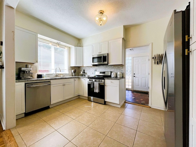 kitchen with white cabinetry, sink, light tile patterned floors, and stainless steel appliances