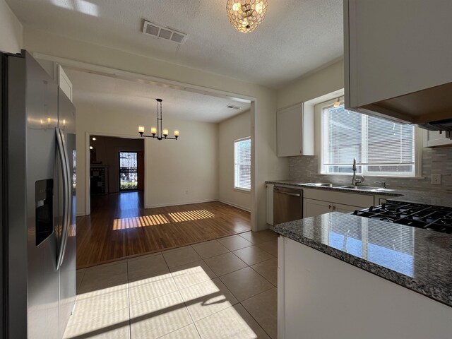 kitchen with white cabinets, hanging light fixtures, light tile patterned floors, tasteful backsplash, and stainless steel appliances