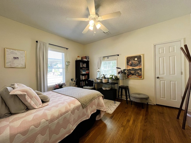 bedroom featuring multiple windows, a textured ceiling, dark hardwood / wood-style flooring, and ceiling fan