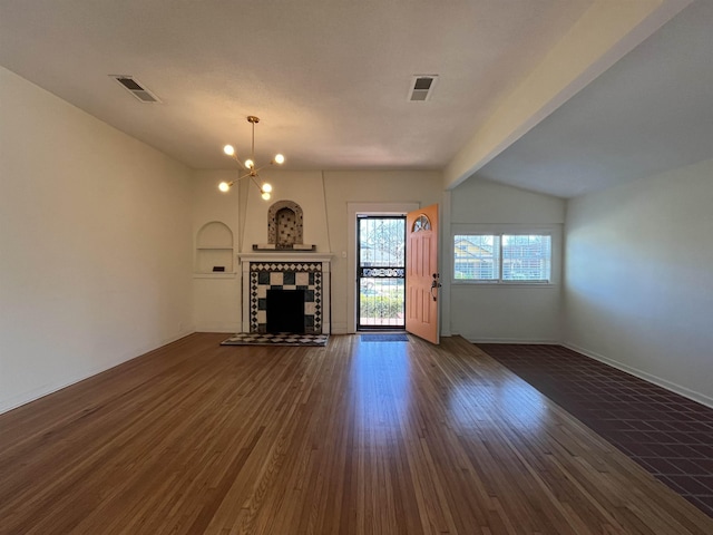 unfurnished living room featuring a tile fireplace, lofted ceiling with beams, dark hardwood / wood-style floors, built in features, and a chandelier