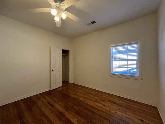 unfurnished bedroom featuring a closet, ceiling fan, and dark wood-type flooring