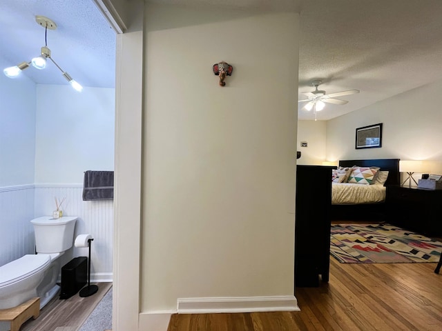 bedroom with ceiling fan, wood-type flooring, and a textured ceiling