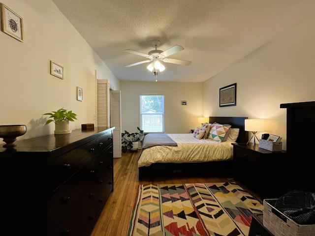 bedroom with ceiling fan, a textured ceiling, and hardwood / wood-style flooring