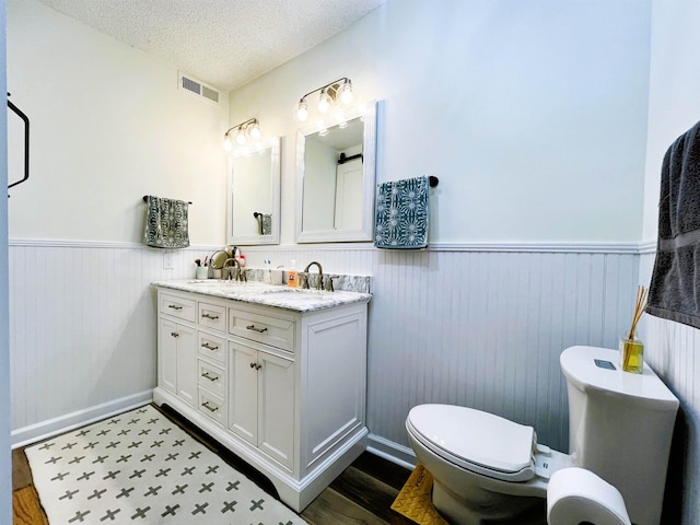 bathroom featuring vanity, a textured ceiling, hardwood / wood-style flooring, and toilet