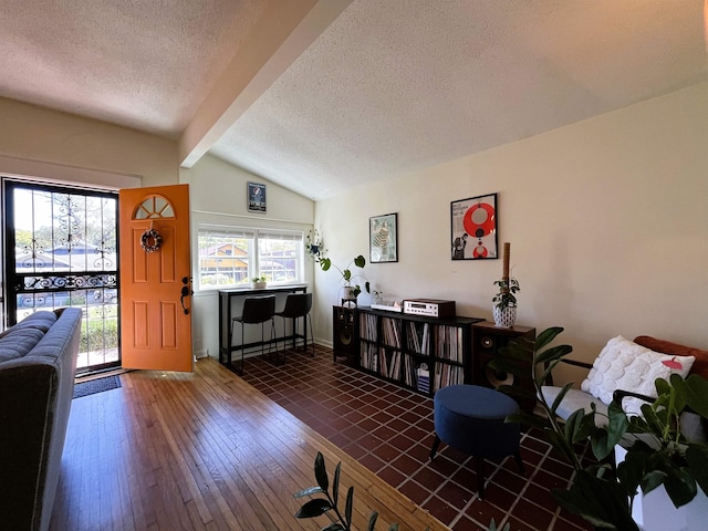 living room featuring dark wood-type flooring, lofted ceiling with beams, and a textured ceiling