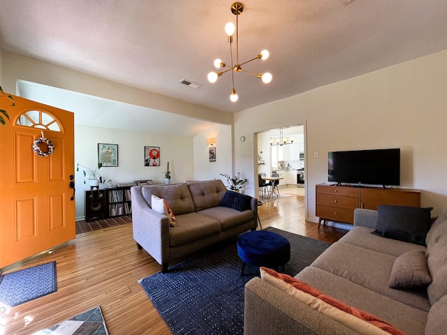 living room with light wood-type flooring and a notable chandelier