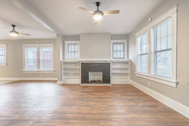 unfurnished living room with hardwood / wood-style flooring, a healthy amount of sunlight, and a brick fireplace