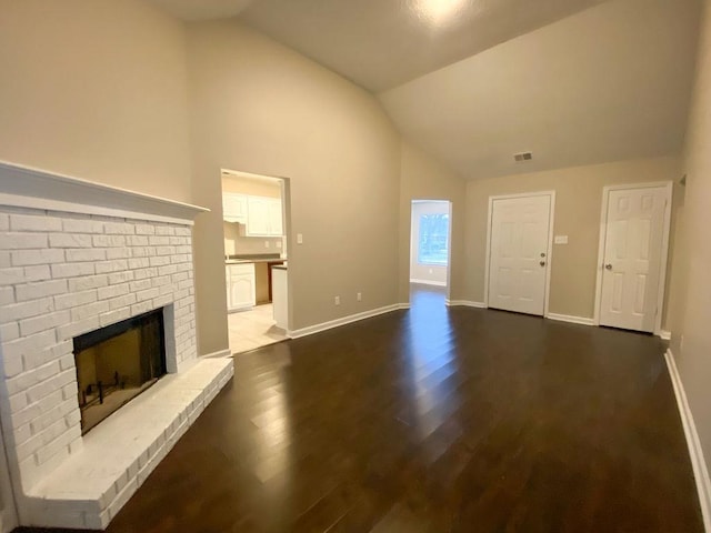 unfurnished living room with lofted ceiling, dark wood-type flooring, and a brick fireplace