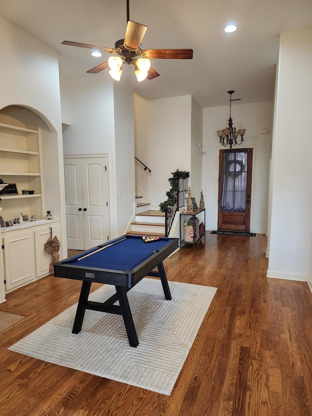 game room featuring built in shelves, ceiling fan with notable chandelier, and dark wood-type flooring