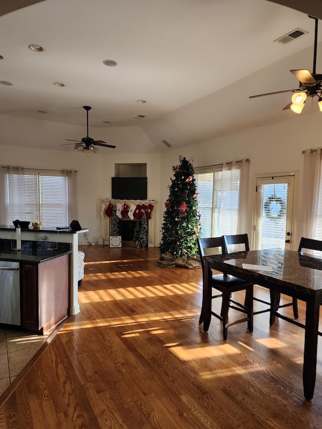 dining space with ceiling fan, dark wood-type flooring, and vaulted ceiling