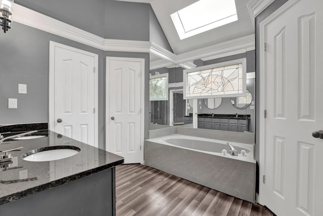 bathroom with hardwood / wood-style floors, vanity, vaulted ceiling with skylight, ornamental molding, and a tub to relax in