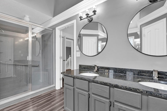 bathroom featuring wood-type flooring, vanity, a shower with door, and ornamental molding