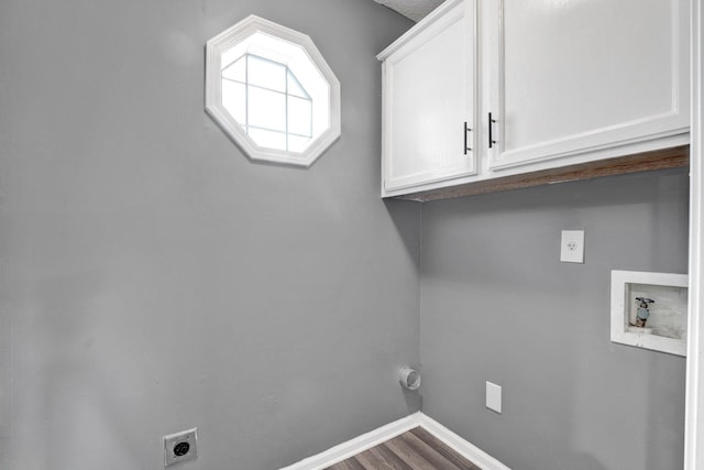 laundry area with electric dryer hookup, hookup for a washing machine, hardwood / wood-style floors, and cabinets