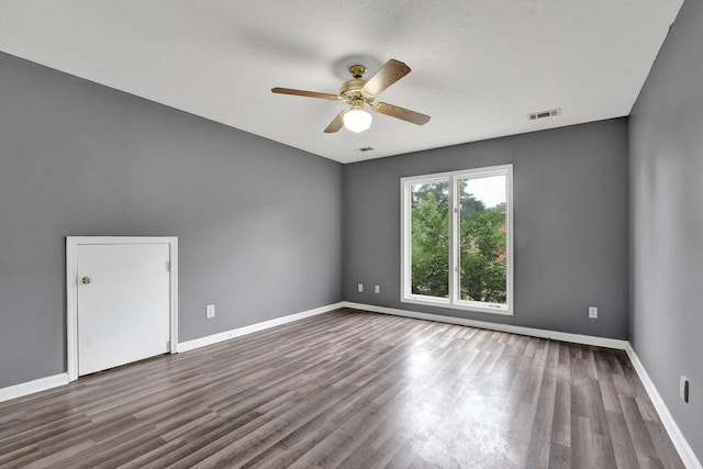 empty room with ceiling fan and dark wood-type flooring