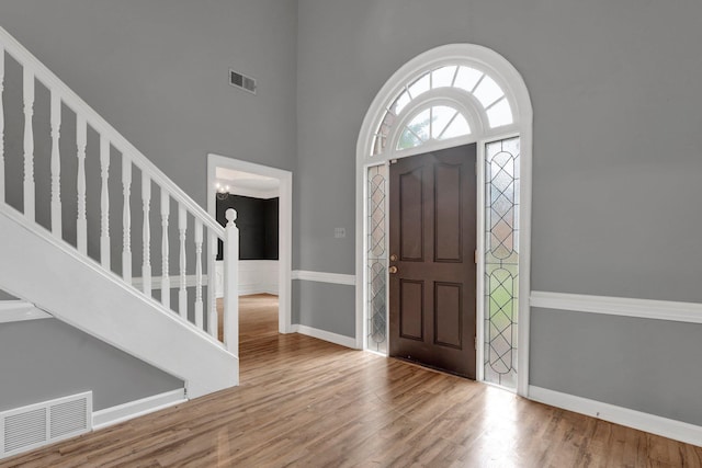 foyer with hardwood / wood-style flooring, a towering ceiling, and an inviting chandelier