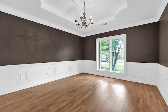 empty room featuring a chandelier, hardwood / wood-style floors, and a tray ceiling