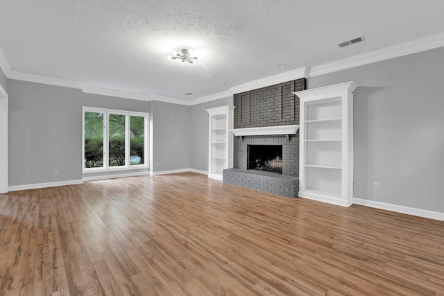 unfurnished living room with hardwood / wood-style floors, a fireplace, ornamental molding, and a textured ceiling