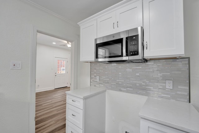 kitchen with tasteful backsplash, crown molding, white cabinets, and ceiling fan