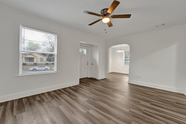 unfurnished living room featuring crown molding, a healthy amount of sunlight, ceiling fan with notable chandelier, and hardwood / wood-style flooring