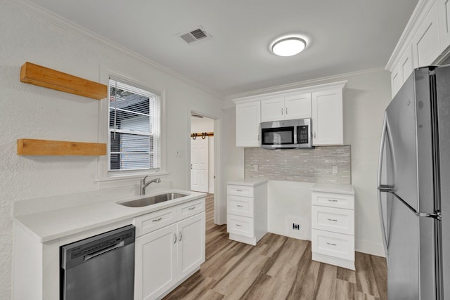 kitchen with crown molding, white cabinetry, sink, and appliances with stainless steel finishes